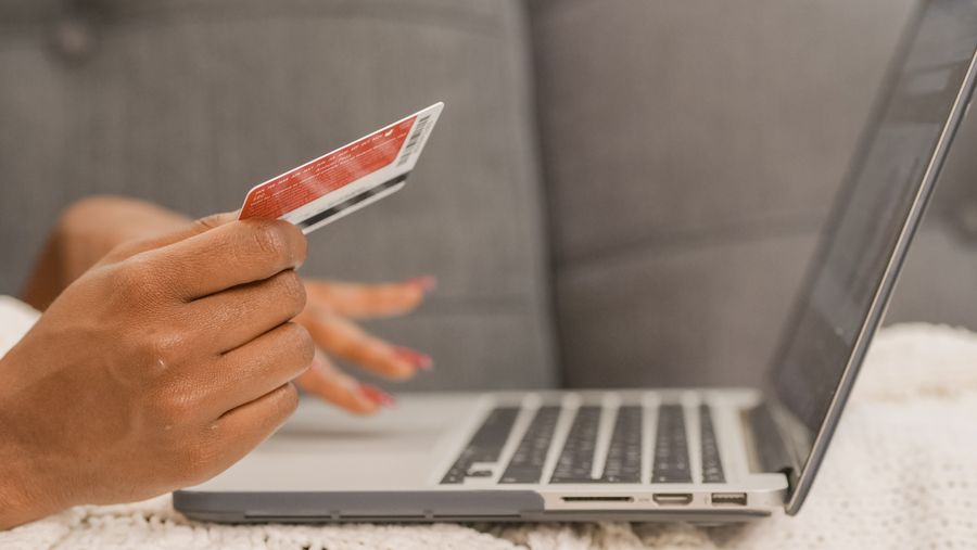 A shopper holding a credit card at a laptop