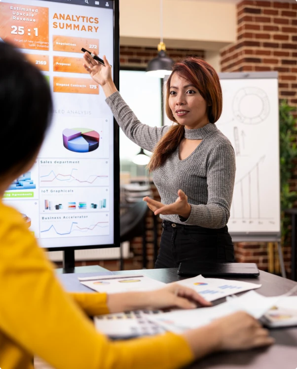 Presenter pointing to an analytics summary on a large screen during a meeting