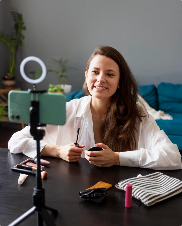 Creator filming a makeup review on a phone with a ring light