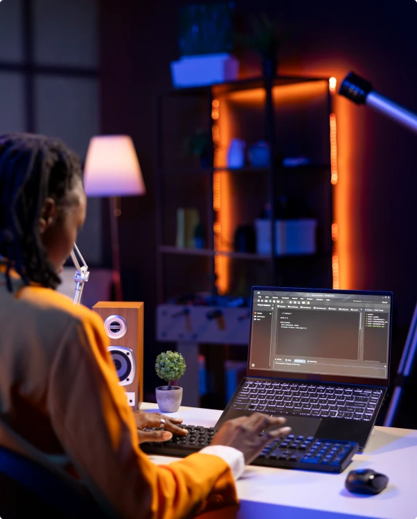 Developer coding on a laptop at a desk at night