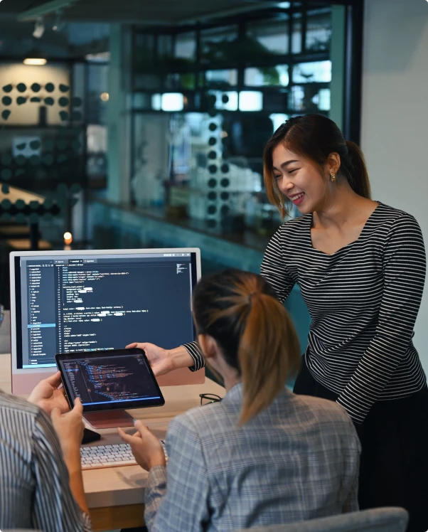 Colleagues reviewing code on a tablet and a monitor in an office