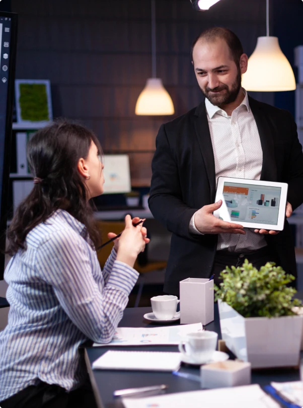Manager presenting a tablet report to a colleague in an office