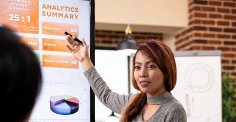 A consultant presenting an analytics summary on a wall screen