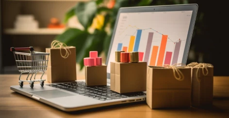 Laptop showing bar charts beside a toy cart and parcels