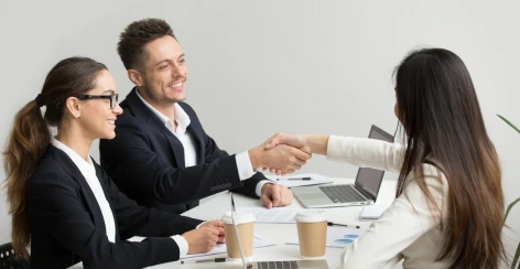 Team shaking hands with a client across a meeting table