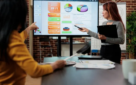 Two colleagues reviewing a campaign dashboard on a large screen