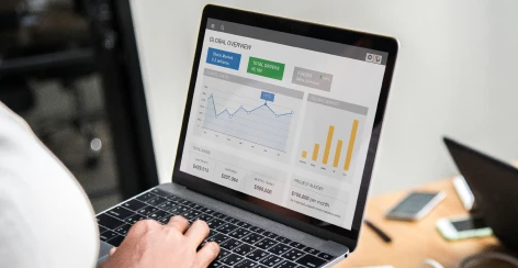 Laptop showing a campaign performance dashboard with line and bar charts