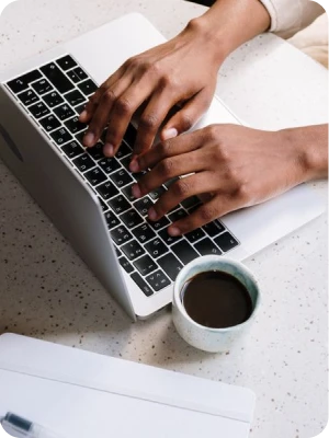 Writer typing a draft on a laptop beside a cup of coffee