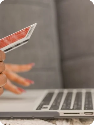 Shopper holding a credit card beside a laptop