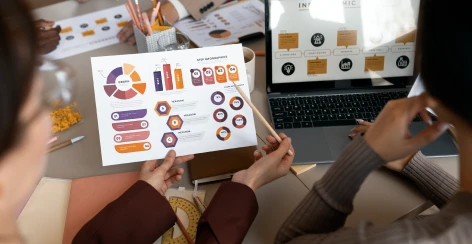 Colleagues reviewing a printed workflow infographic beside a laptop