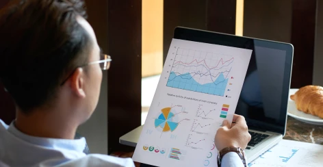 Professional reviewing a printed campaign report beside a laptop