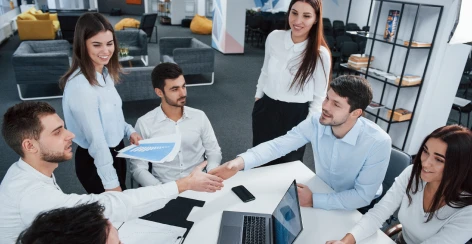 Professional services team shaking hands around a meeting table