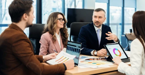 Consultants meeting with a client team around a table of reports