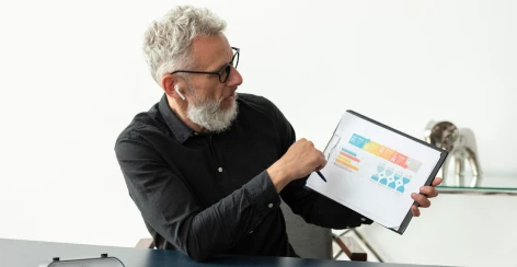 Man pointing a pen at a chart on a tablet