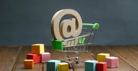 Toy shopping cart holding an @ symbol among colorful blocks