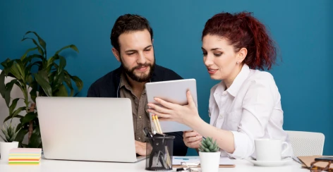 Two colleagues looking at a tablet beside a laptop