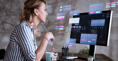 Woman with a coffee studying a dashboard on a desktop monitor