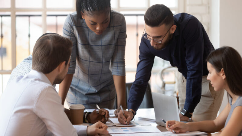 sales team gathered around a desk discussing digital transformation