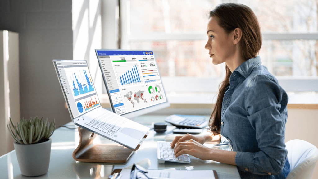 Digital marketing lady on two monitors reviewing analytics for a Toronto based client in CDAP program