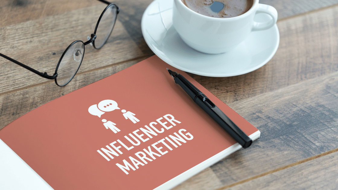 grow with influencer marketing - notebook with influencer marketing written on it, next to a coffee and a pair of glasses